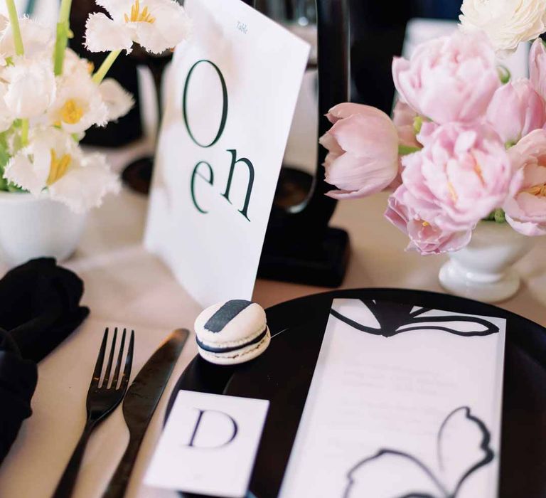 White monochrome wedding stationery on light pink wedding tablecloth and black quirky wedding candlestick 