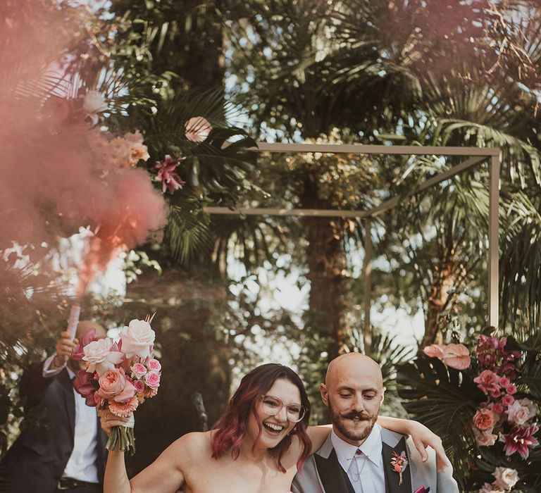 bride in strapless wedding dress and groom in a grey suit dancing up the aisle as husband and wife at their outdoor Italian villa wedding venue