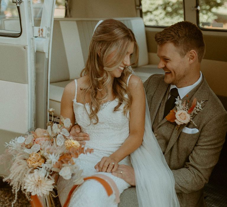 Bride and groom sit together in VW camper van wedding transport 