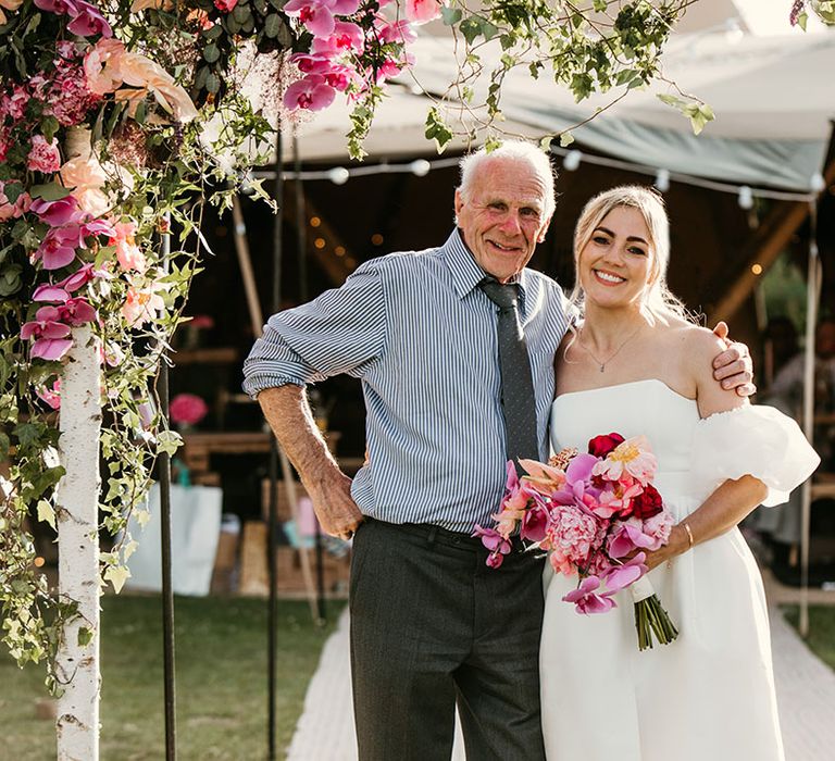 Bride and grandad pose together for special wedding photo with pink wedding flowers 