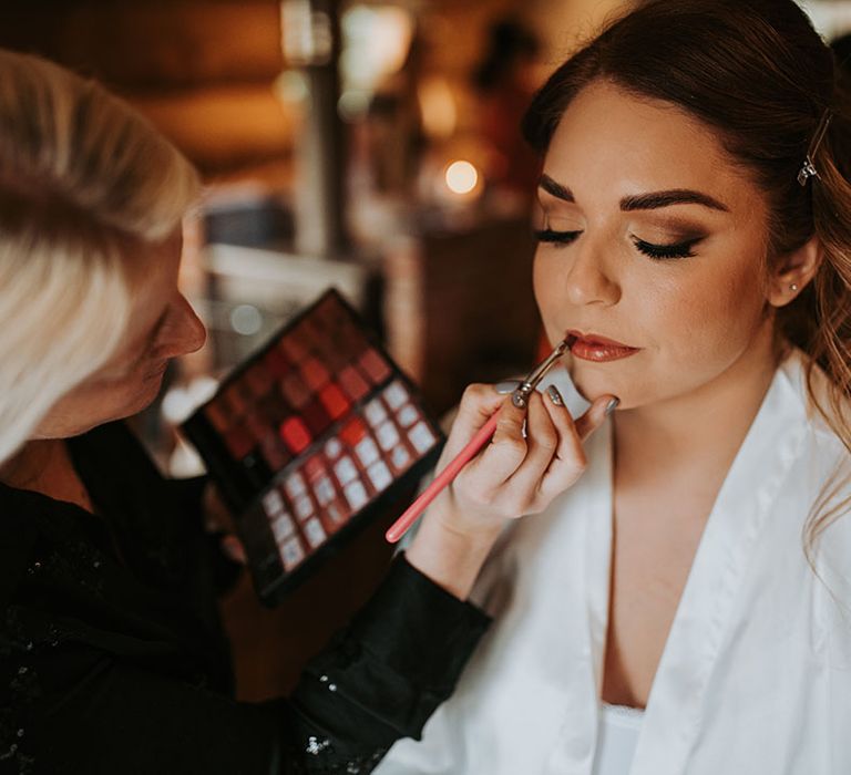 Bride sits getting her wedding makeup done for the big day 