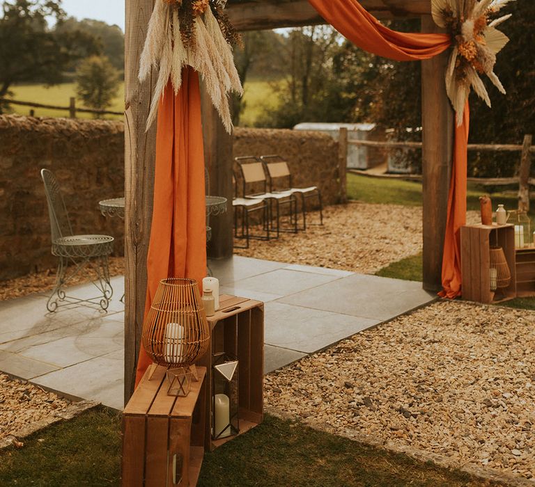 Outdoor wedding ceremony set up with dried wedding flowers and orange drapery wedding decor 