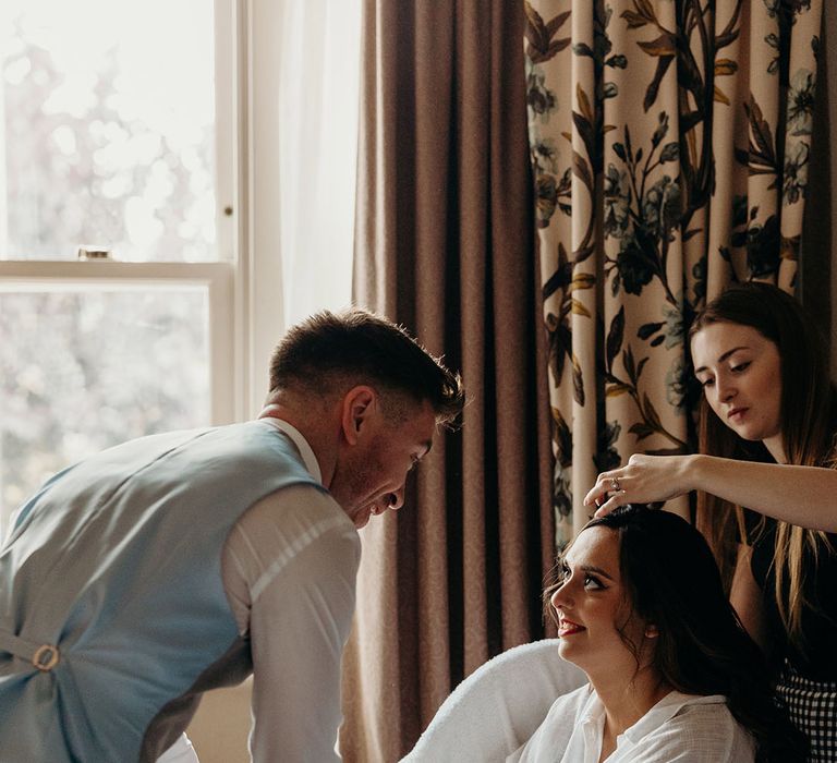 Man of honour helps the bride as she gets ready on the morning of the wedding 