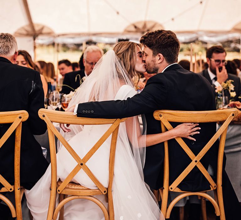 bride in a Suzanne Neville wedding dress kissing her groom in tails at their marquee Sennen Cove wedding 