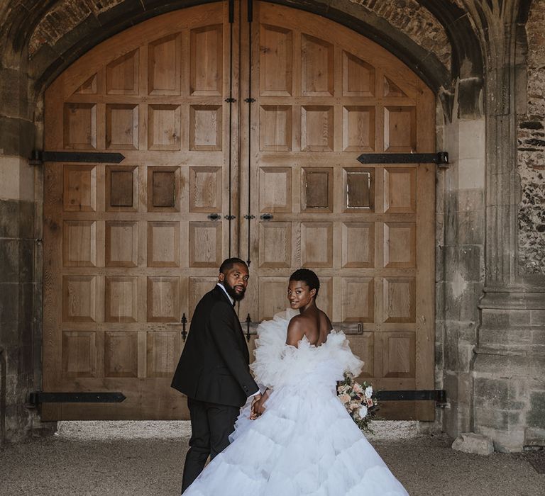 Medieval wedding at Pentney Abbey Norfolk wedding venue with bride in tulle off the shoulder gown and groom in black tie 