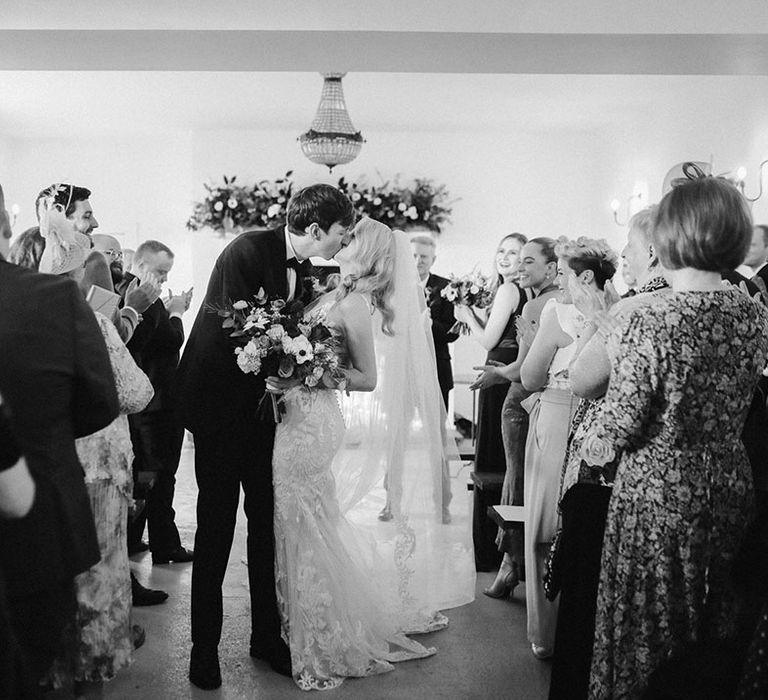 The bride and groom share a passionate kiss as they walk back down the aisle together 