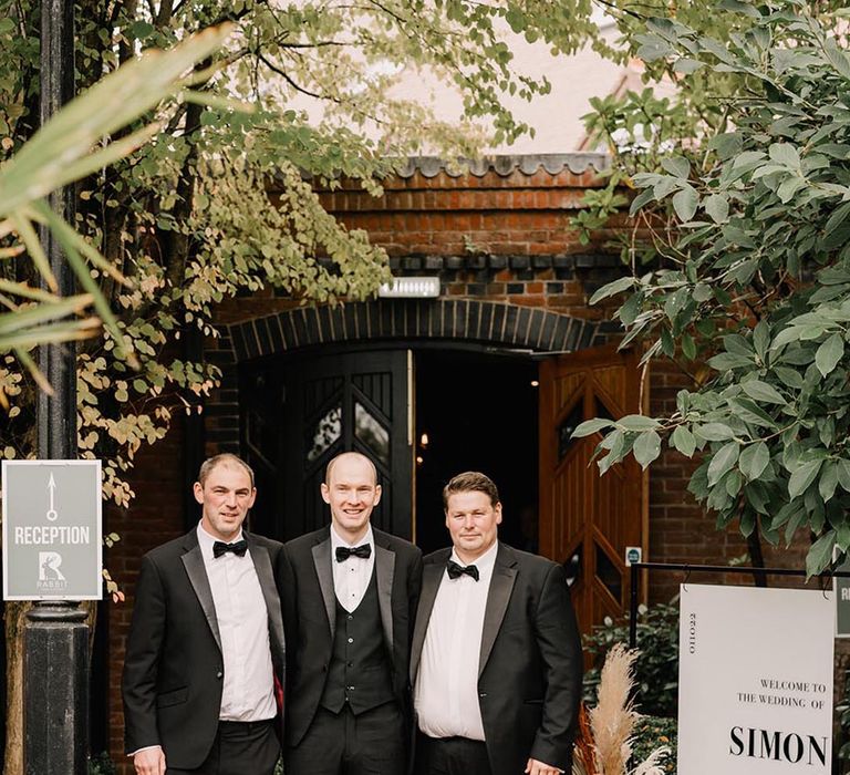 Groom and groomsmen wearing black tuxedos 