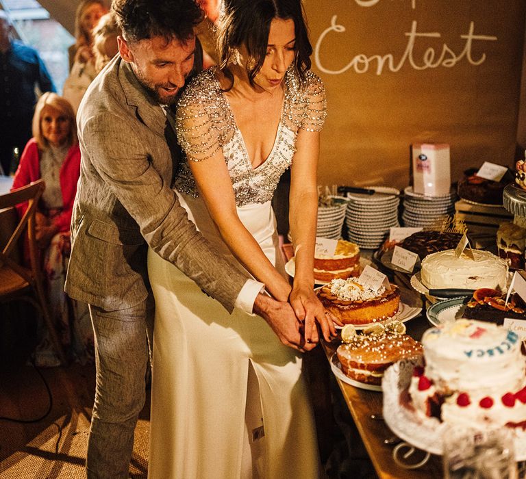 Wedding cake contest and dessert table of cakes with one being cut by the bride and groom 