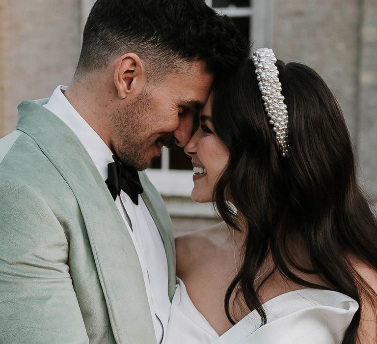 Groom in mint green three piece tuxedo with the bride in an off the shoulder Pronovias wedding dress with pearl headband 