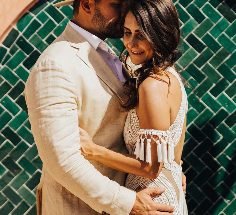 Groom wearing hat embraces the bride for couple photo at boho wedding 