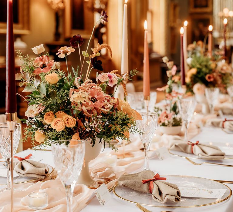 Dark red and orange wedding flowers and candles decorating the autumn wedding theme table