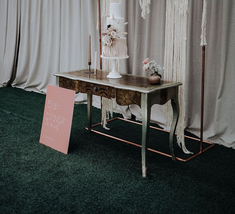 Macarame backdrop decoration behind the traditional white wedding cake with dried flowers and bunny grass 