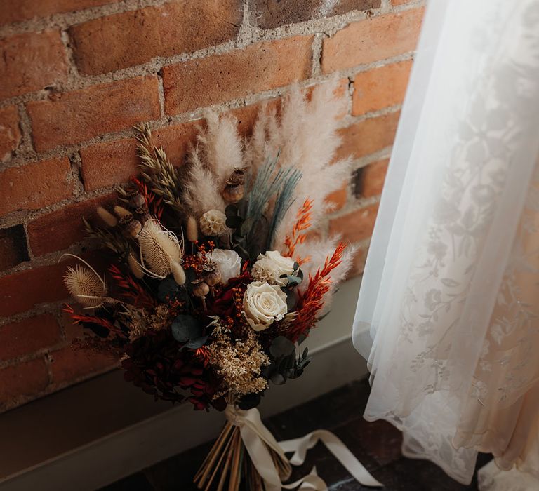 Dried wedding flower bouquet with bunny grass for autumnal wedding next to the pearl bridal shoes 