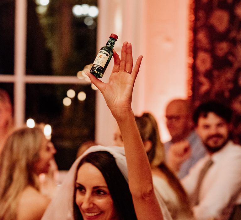 Bride holding bottle of Jameson for the wedding favours 