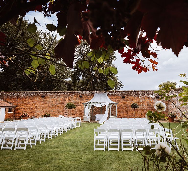 Outdoor wedding ceremony with white chairs and white chuppah for interfaith wedding with Islamic and Jewish wedding ceremony 