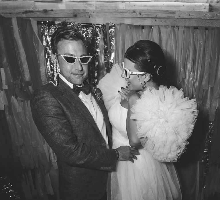 Streamer decorations as photo backdrop with bride and groom posing together with sunglasses 