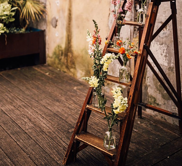 Rustic wedding decor with flowers decorating wooden ladder 