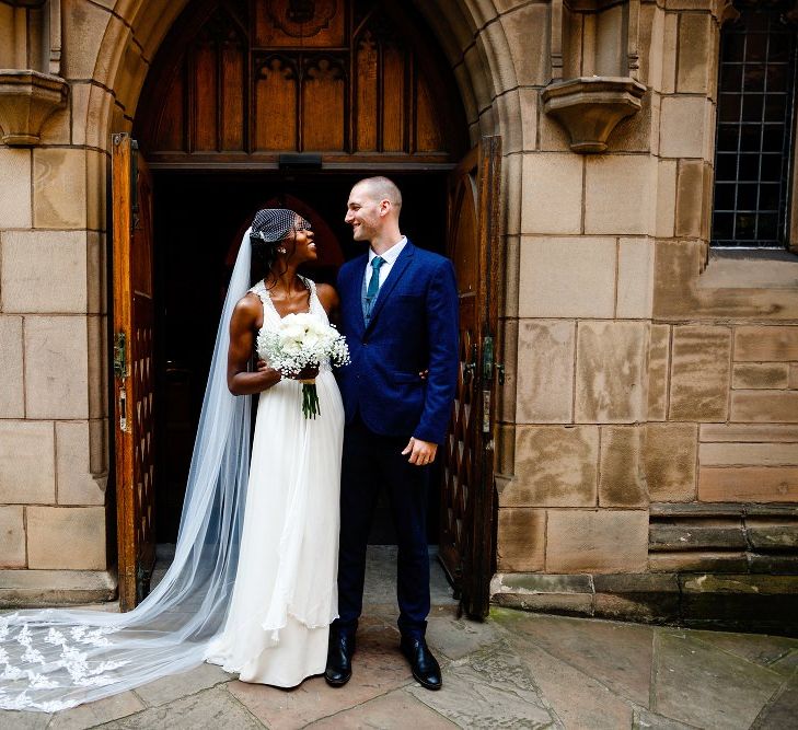 Bride in halterneck Jenny Packham wedding dress and lace edged cathedral length veil 