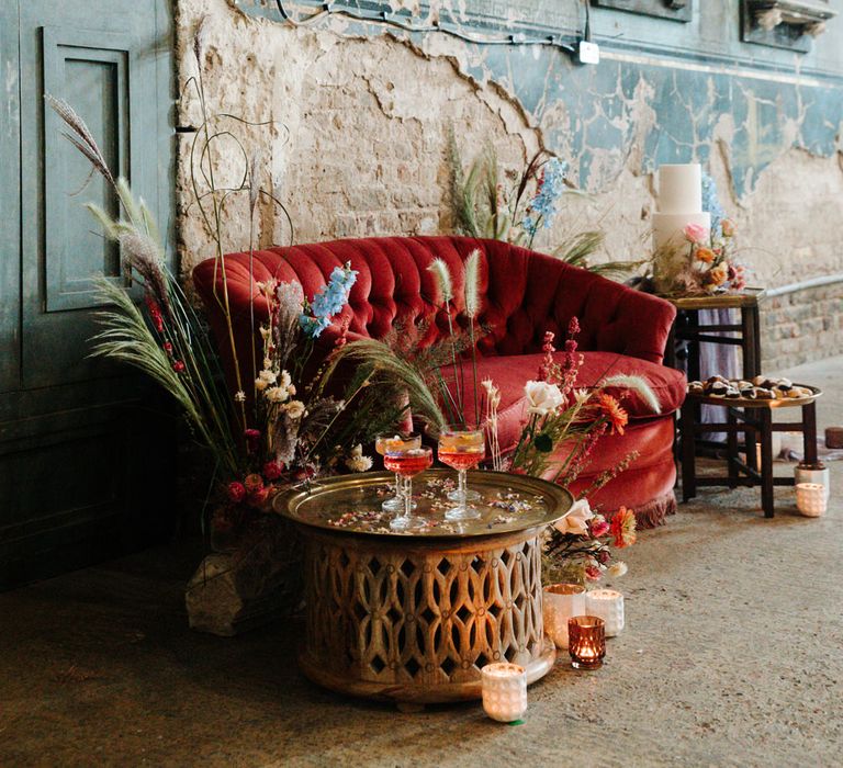 Intimate seating area with red velvet sofa, cocktails and cake table 