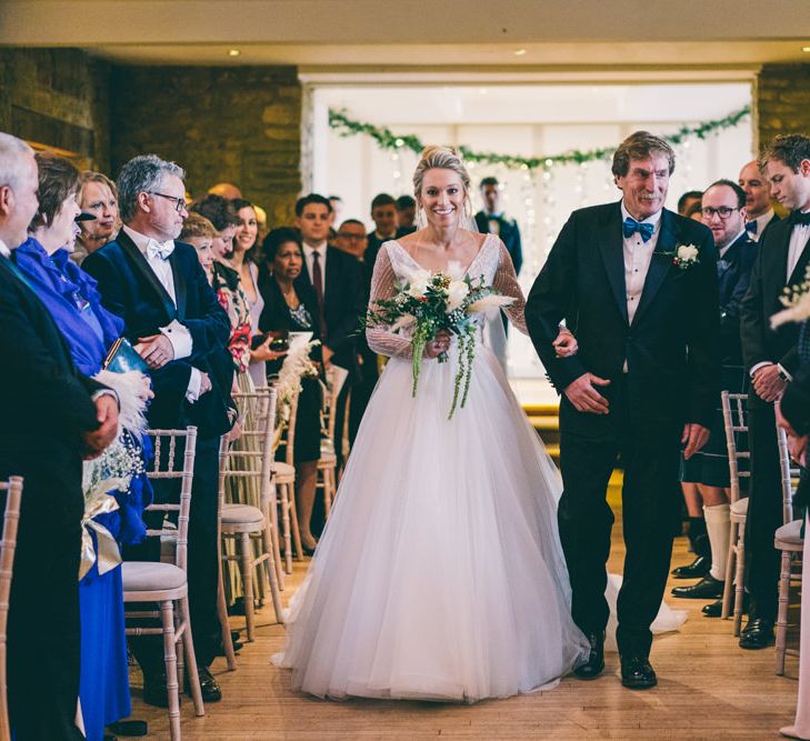 Father of the bride walking his daughter down the aisle in an embellished Enzoani wedding dress