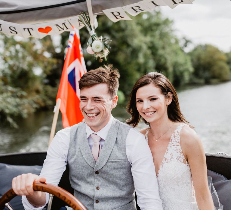 Groom steers boat during wedding reception with bride sat next to him 