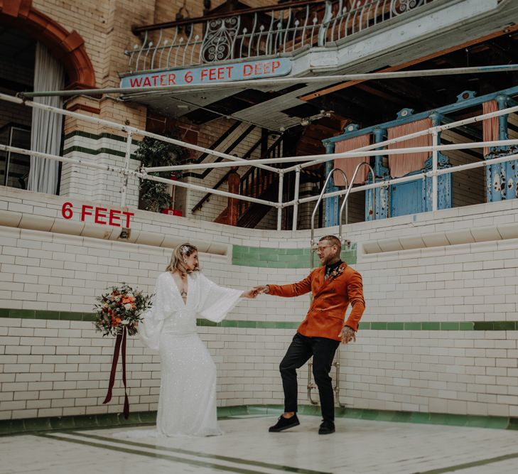 Bride and groom dancing in abandoned swimming pool