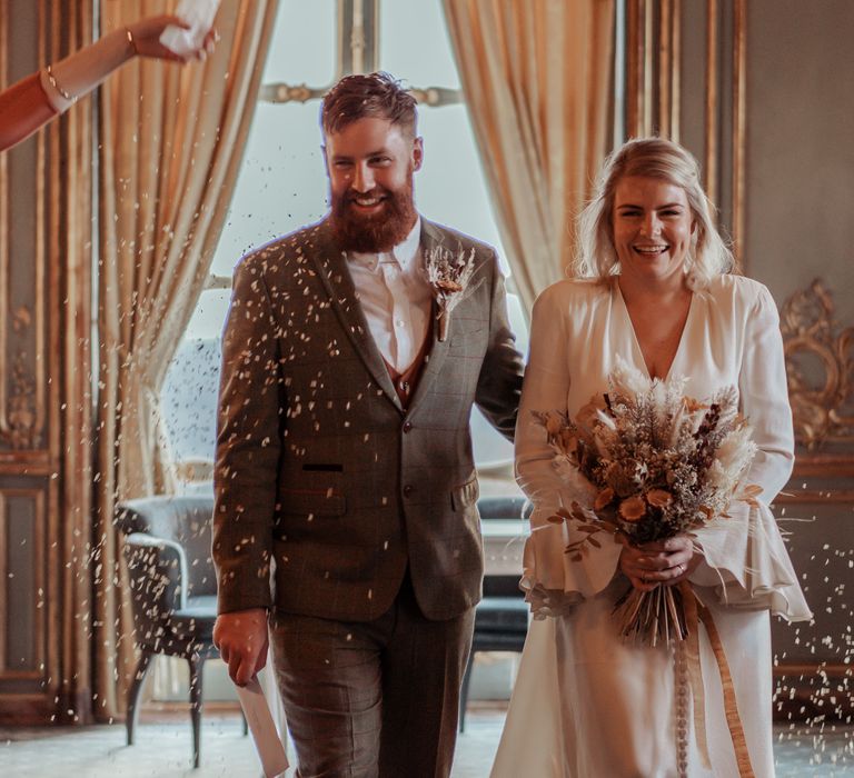 Bride & groom walk together with dried floral bouquet 