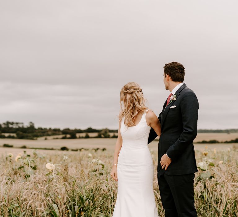 Bride and groom photography in a rural field with bride in fitted wedding dress