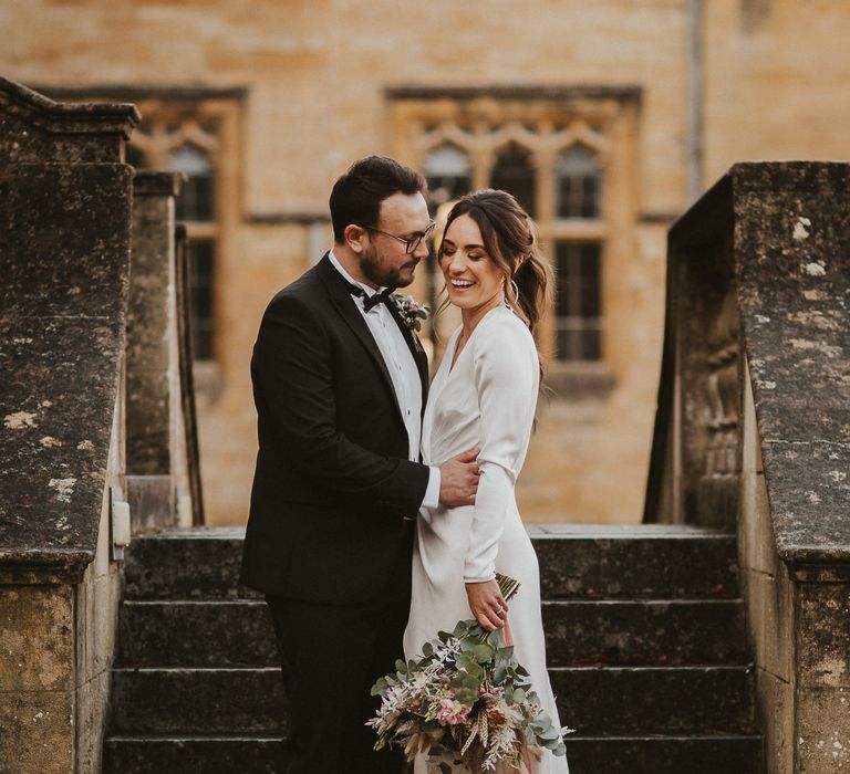 Bride & groom stand together on staircase outdoors 