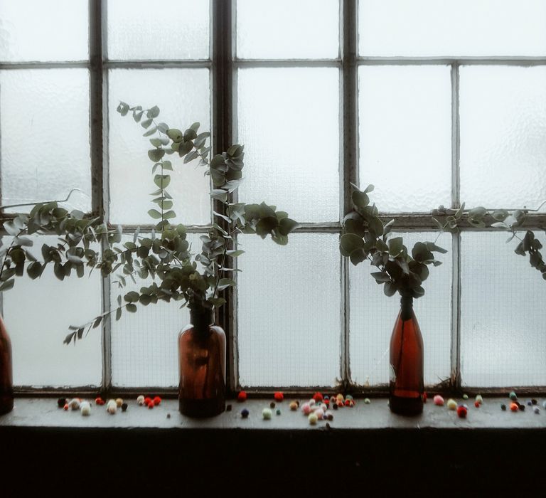 Brown bottles filled with eucalyptus sitting on a window ledge 