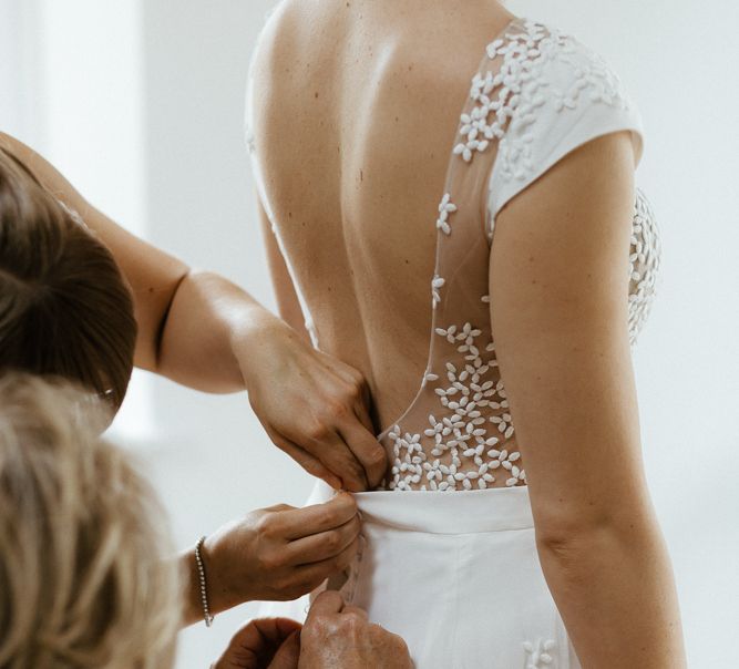 Bride has dress buttoned from the back in an illusion low back wedding gown 