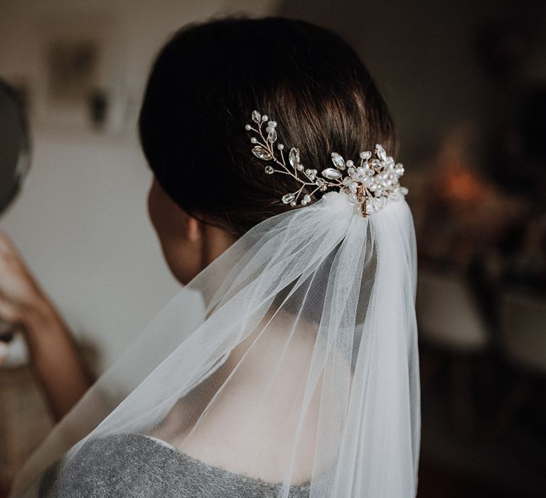 Bride wearing pearl detail hair accessory and veil looks in mirror