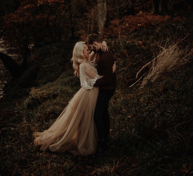 Bride in a beige tulle wedding dress with floaty lace sleeve detail 