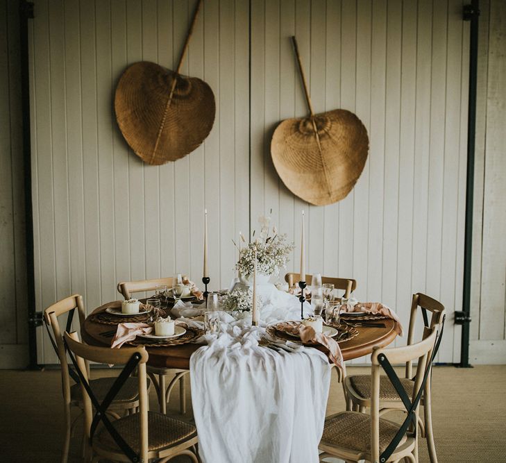 Intimate boho wedding table with natural linen, candles, dried flowers and bamboo fans 