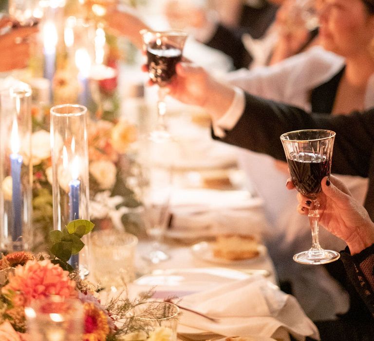 Raising a glass of red wine to toast at the dinner table