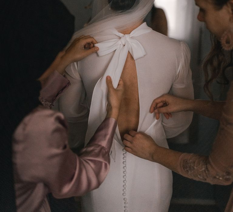 Wedding party helps with brides wedding gown on her wedding day