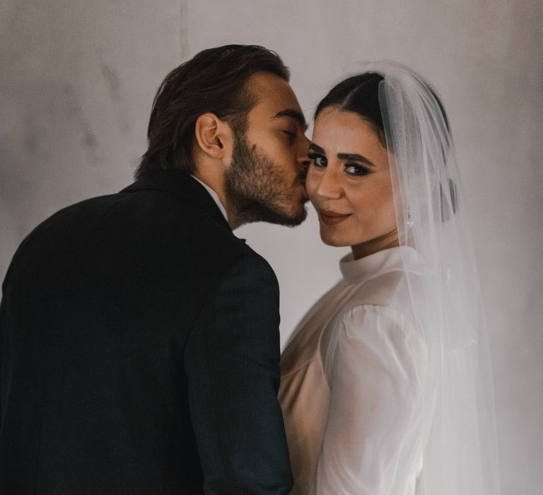 Groom kisses the cheek of his bride on their wedding day