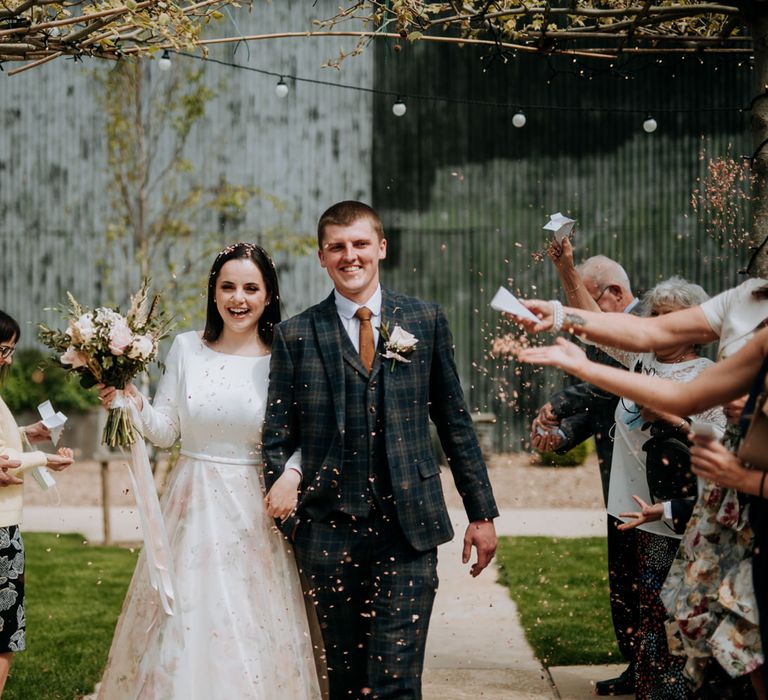 Confetti moments at East Yorkshire Barns with the bride in a floral skirt wedding dress and groom in a navy check suit 