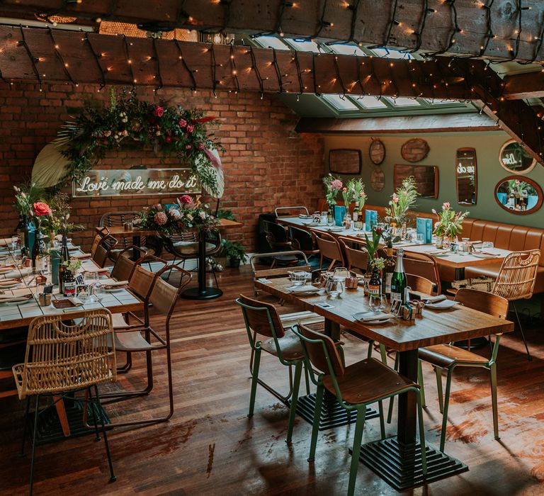 Horticulture wedding reception with wooden tables filled with brightly coloured florals and green foliage