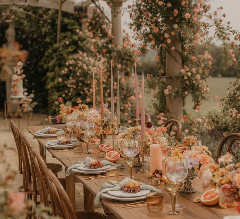 Zingy wedding table decor with orange candles, blush flowers and gold accents 