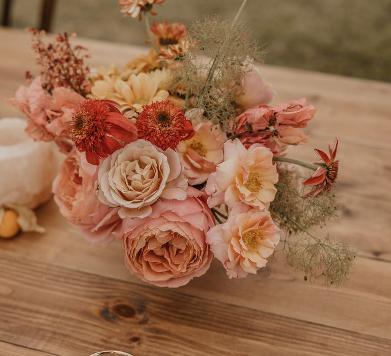 Wedding centrepiece with pastel orange, pink, coral and peach flowers 