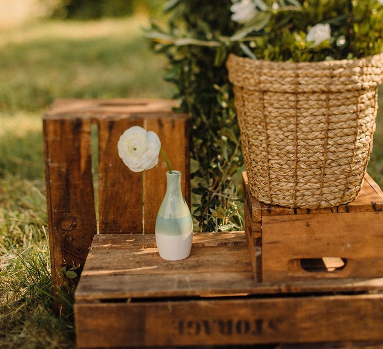 Rustic styling for Croatian wedding complete with wooden boxes, wicker basket and small vase with single white flower