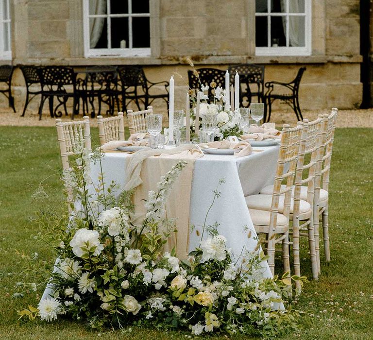 Intimate outdoor tablescape with white and green wedding flowers and taper candles 