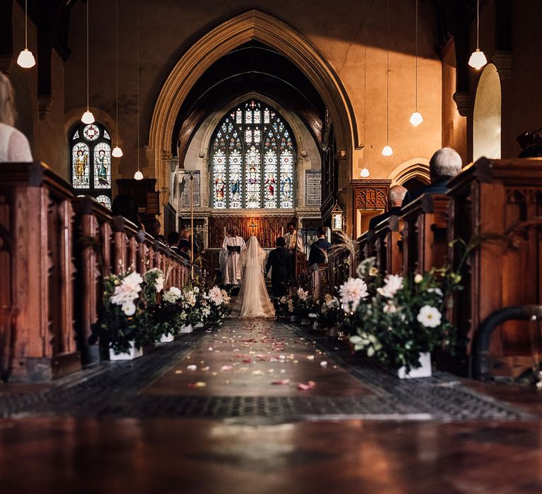 Bride in Halfpenny London Mayfair dress and groom in suit stand at the altar during church ceremony in Cornwall