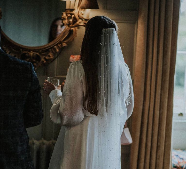 Bride wears her brown hair down straight complete with a floor-length pearl veil