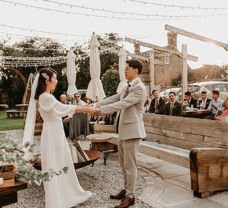 Bride & groom hold hands and look lovingly at one another outdoors on their wedding day