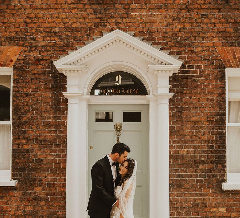 Bride & groom kiss in doorway on their wedding day