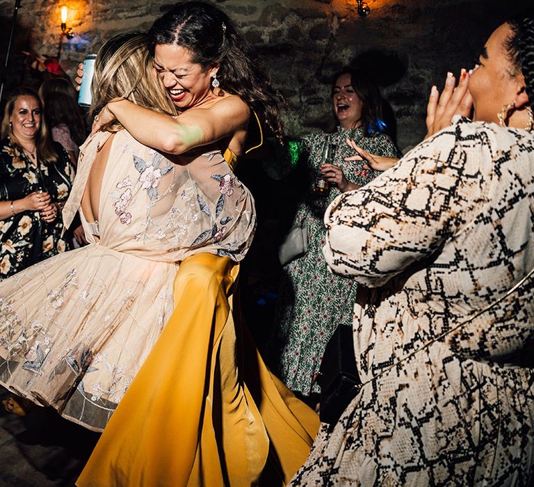 Bride hugs wedding guest during reception on dancefloor 