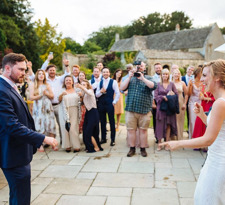 Outdoor surprise first dance at Caswell House wedding venue with bride in an embellished Made With Love wedding dress and groom in a navy blue suit 