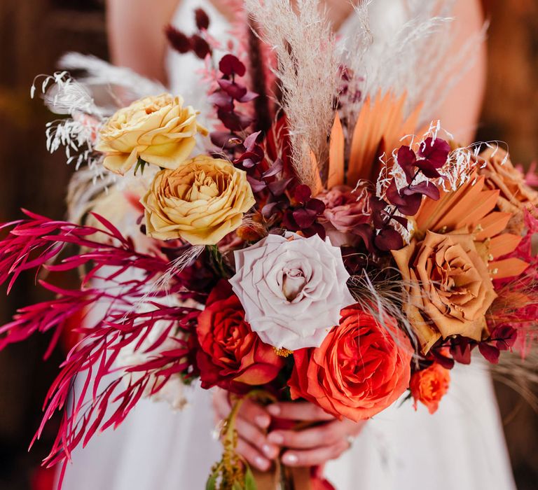 Yellow, red and dusky orange rose bouquet with mixed dried florals for festival style wedding